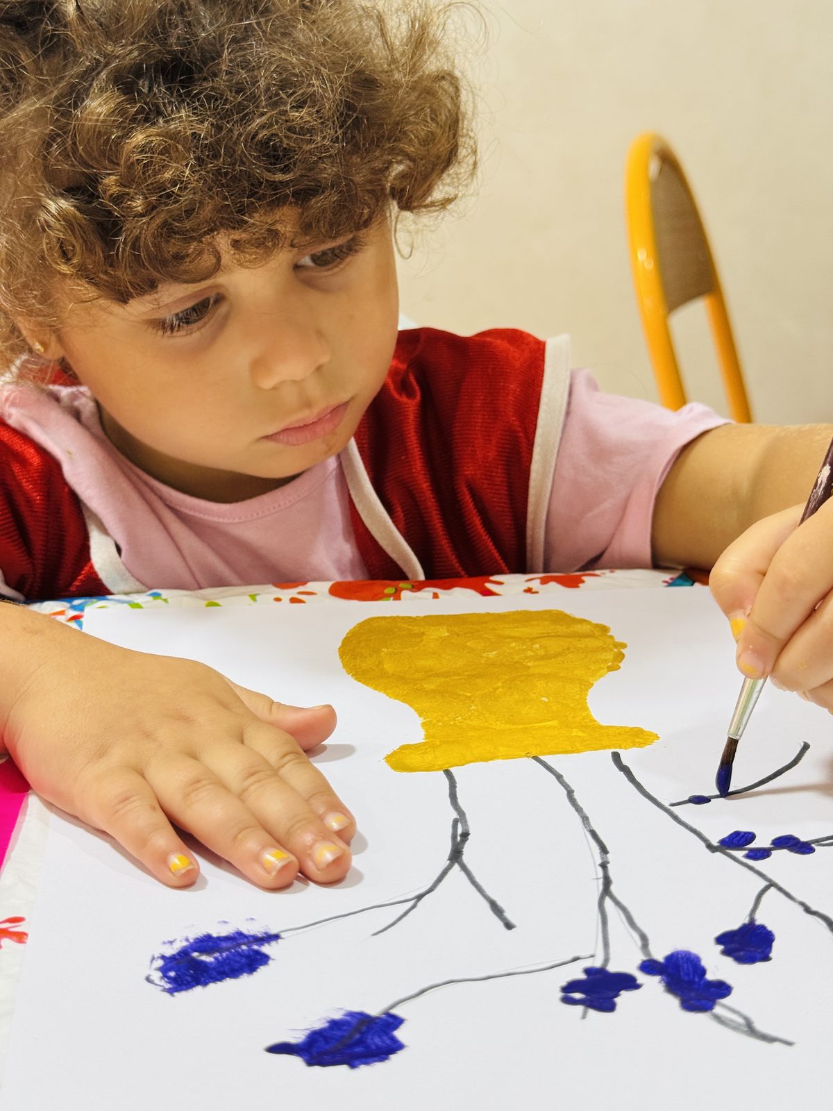 Un enfant peint un arbre en atelier d'arts plastiques